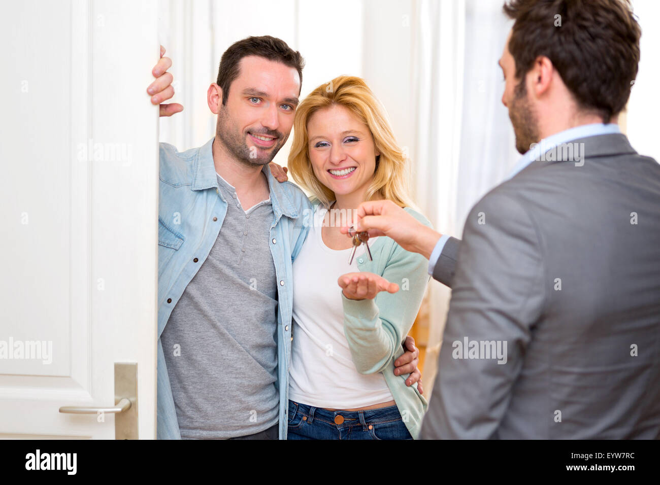 View of a Real estate agent delivers keys of new house to young couple ...