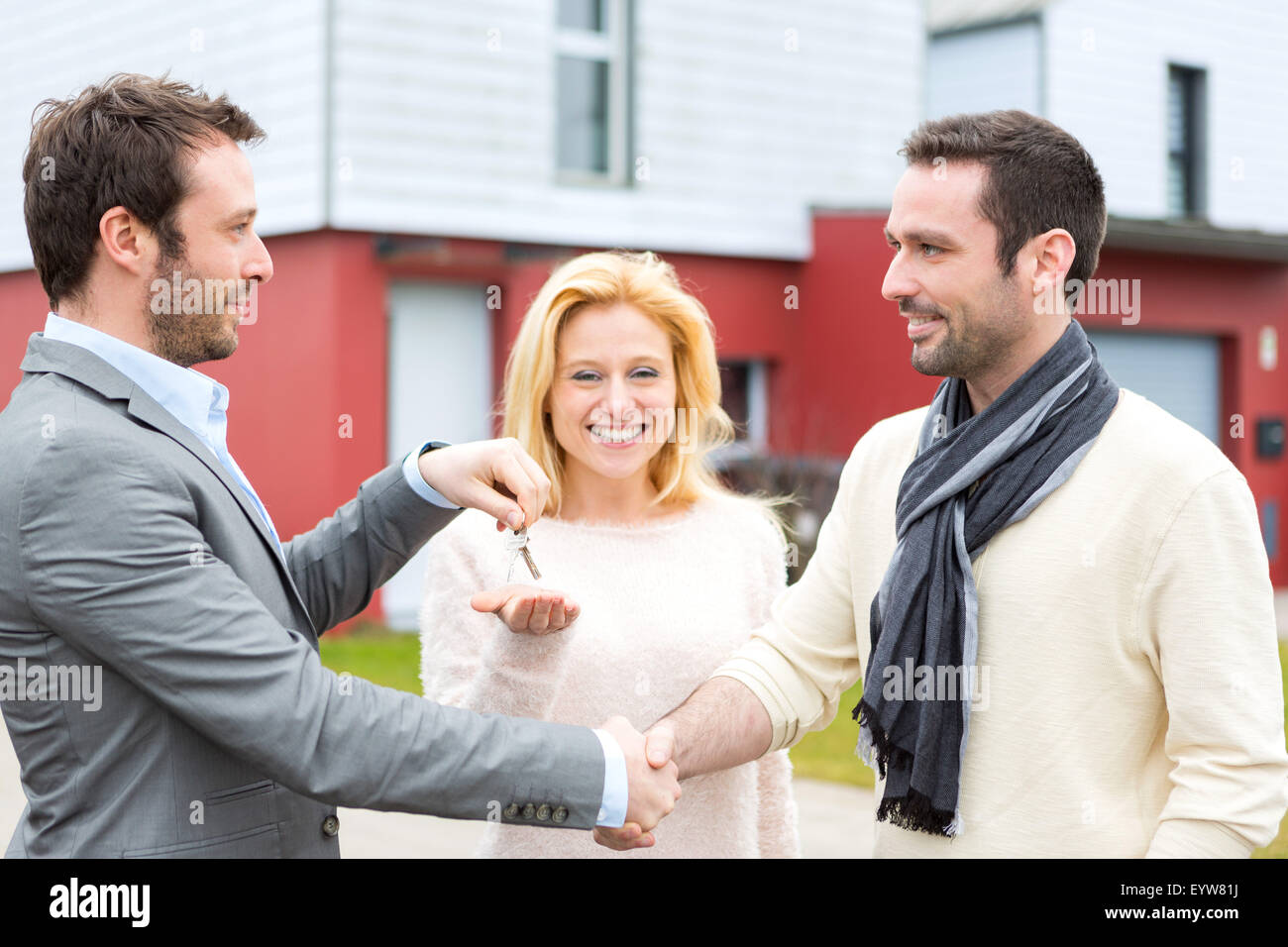 View of a Real estate agent delivers keys to young atractive couple ...