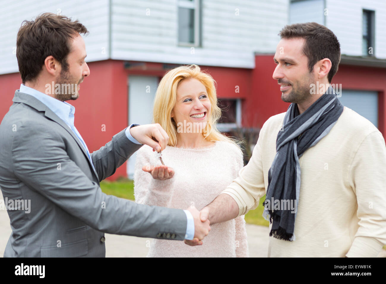 View of a Real estate agent delivers keys to young atractive couple ...