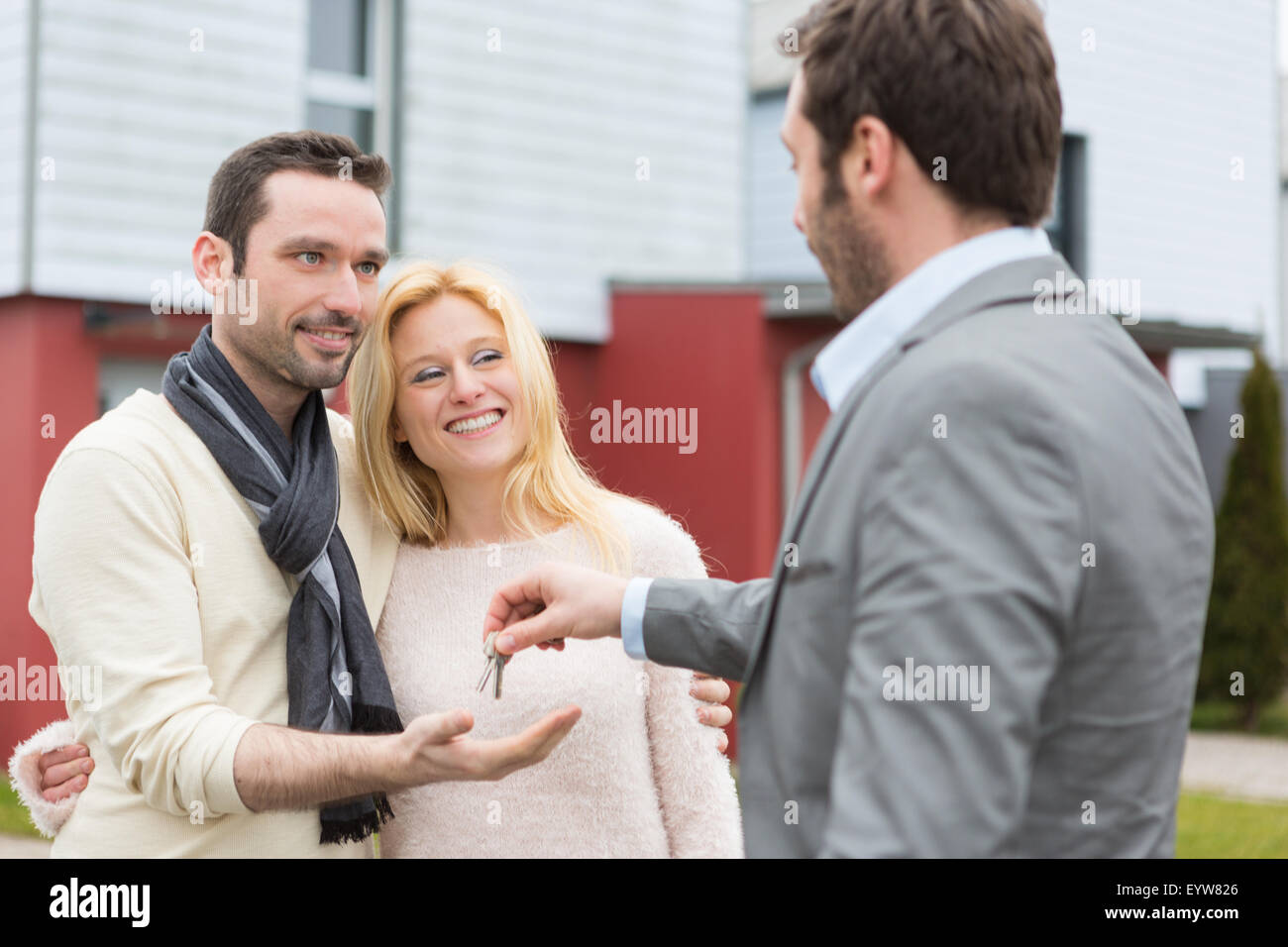 View of a Real estate agent delivers keys to young atractive couple ...