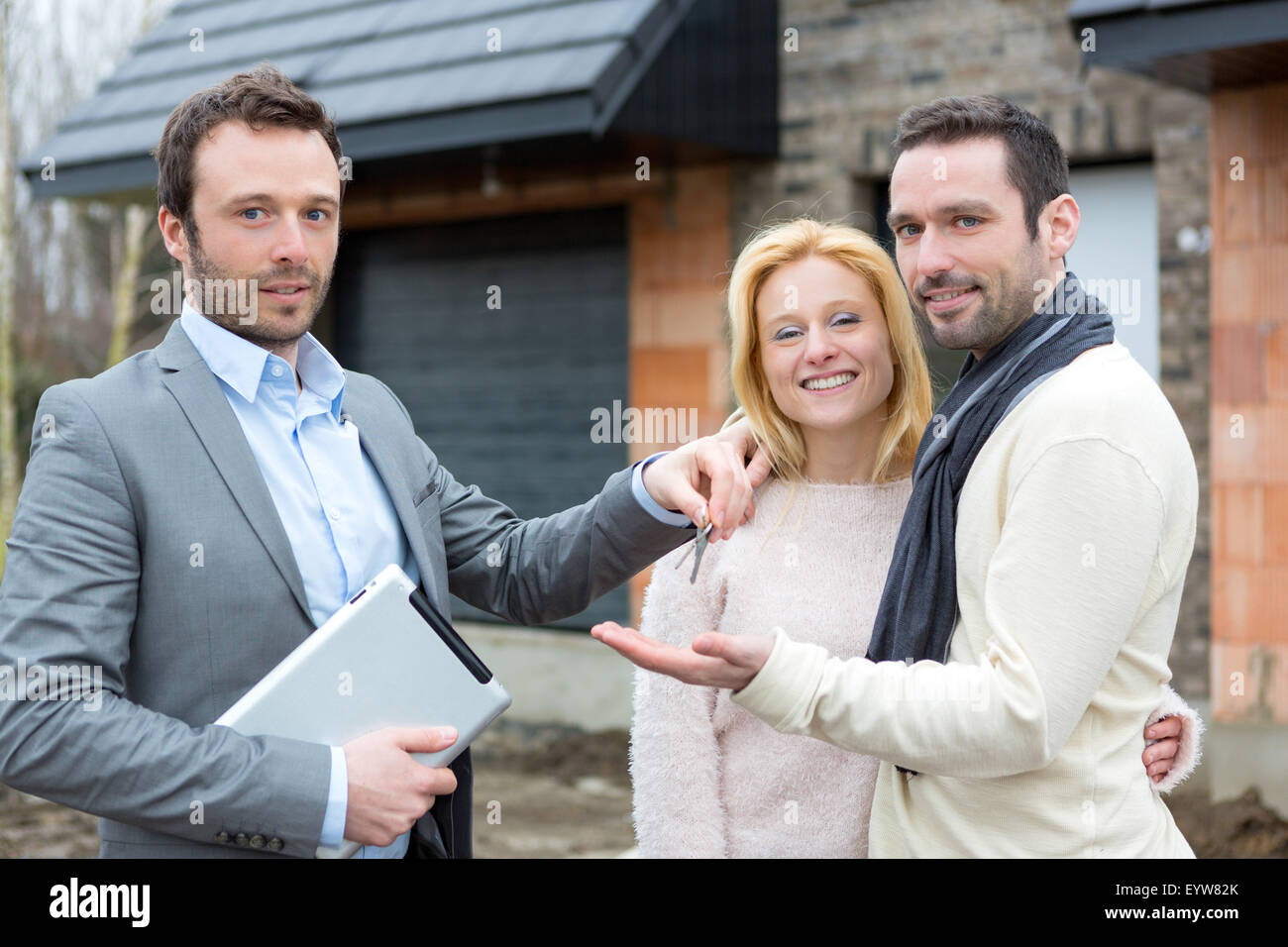 View of a Real estate agent delivers keys to young atractive couple ...