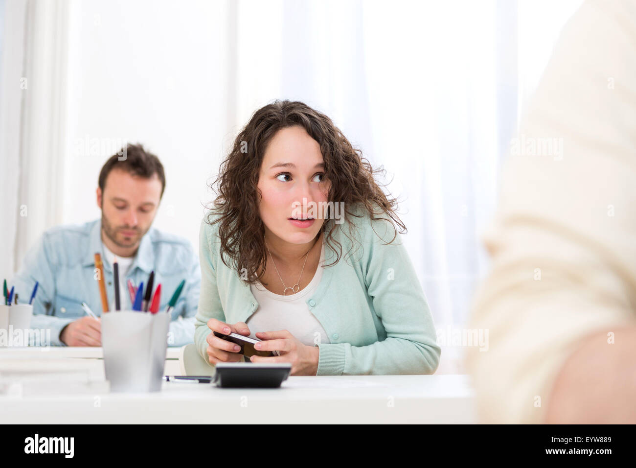 View of a Young attractive woman cheating with mobile during exam Stock Photo