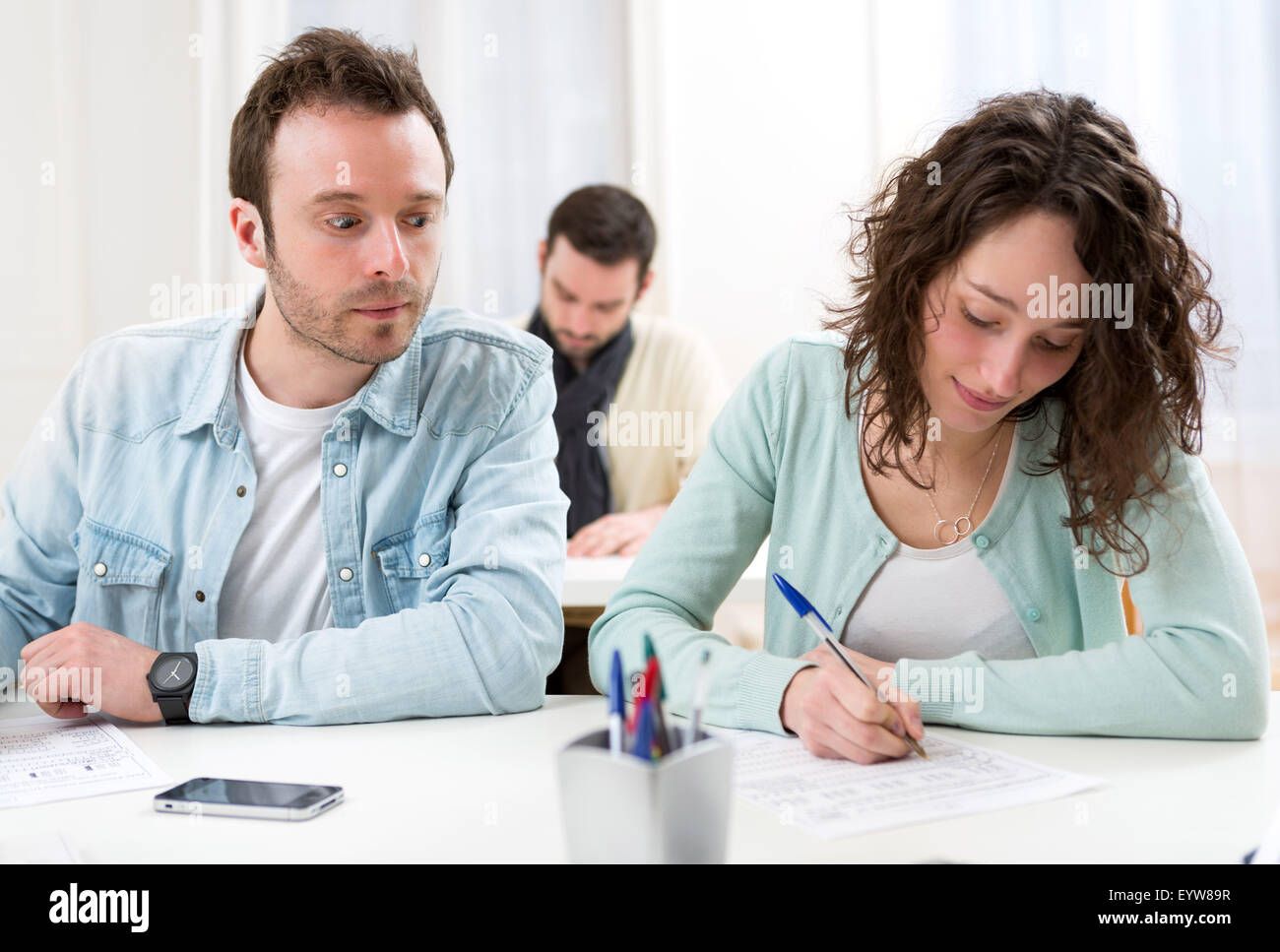 View of a Classmate try to cheat on his neighbour Stock Photo