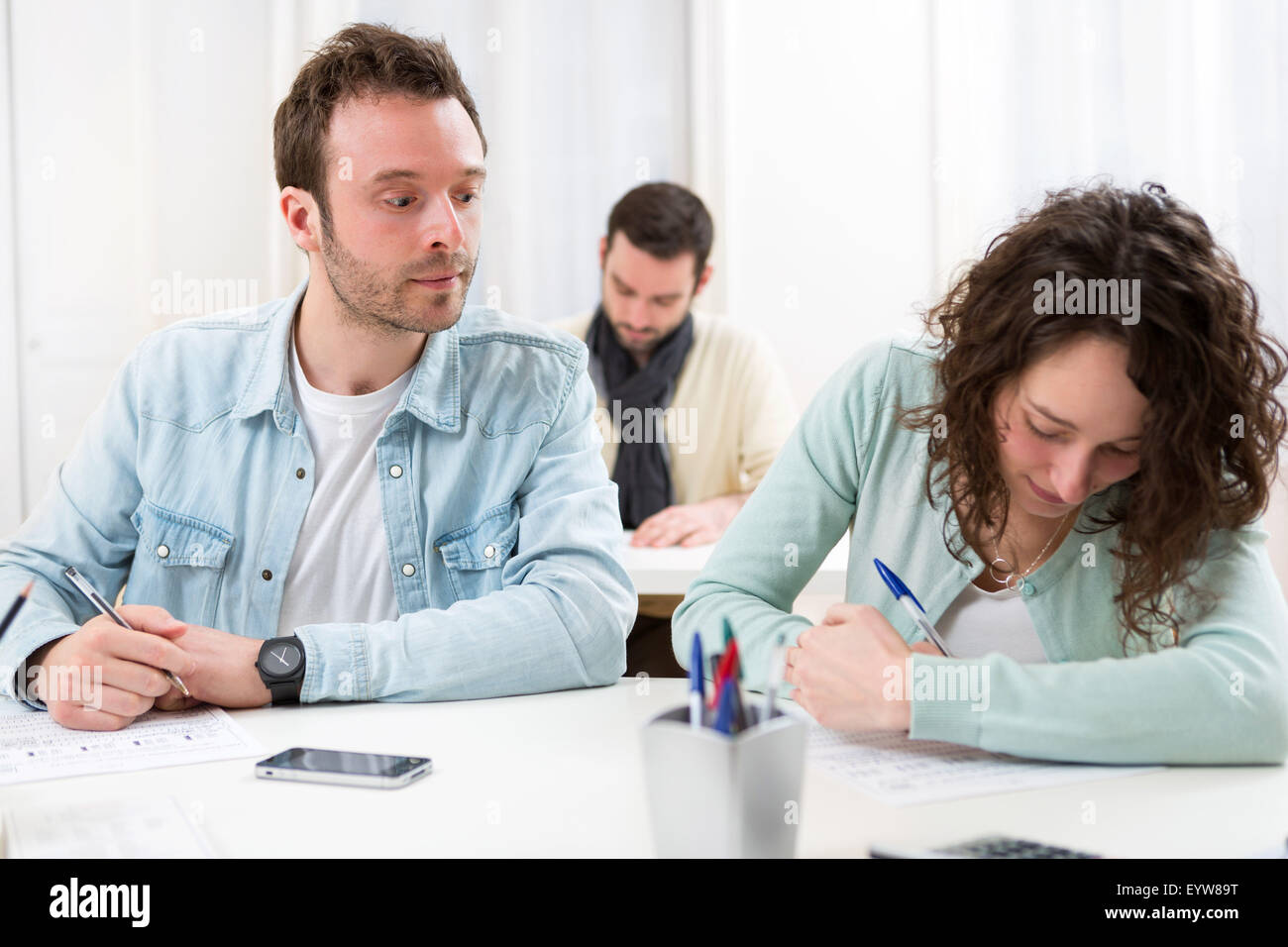 View of a Classmate try to cheat on his neighbour Stock Photo