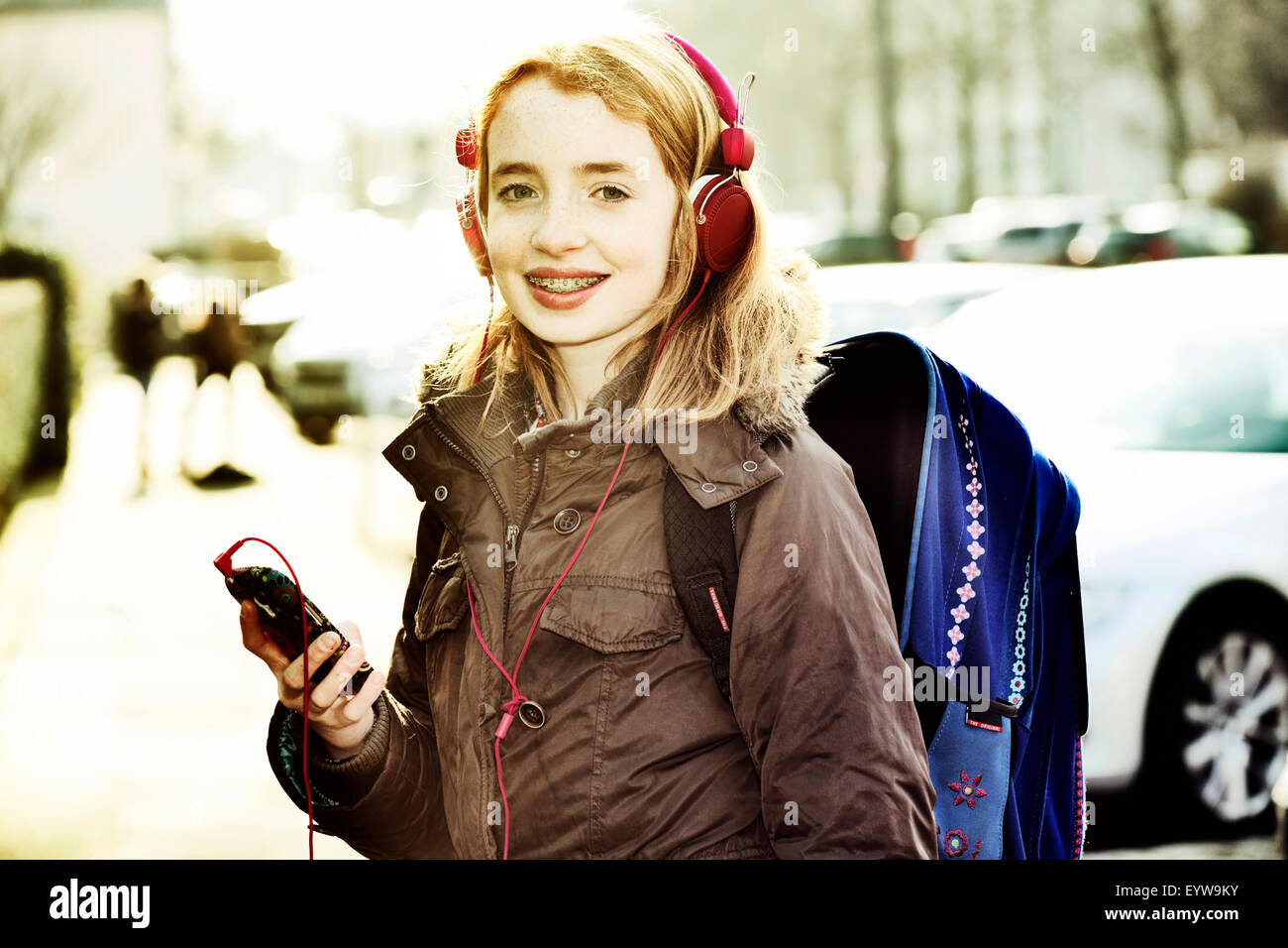 Girl with schoolbag, headphones and mobile phone on the way to school Stock Photo