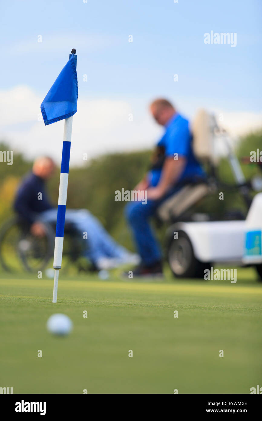 Two men with spinal cord injuries waiting at golf putting green Stock Photo
