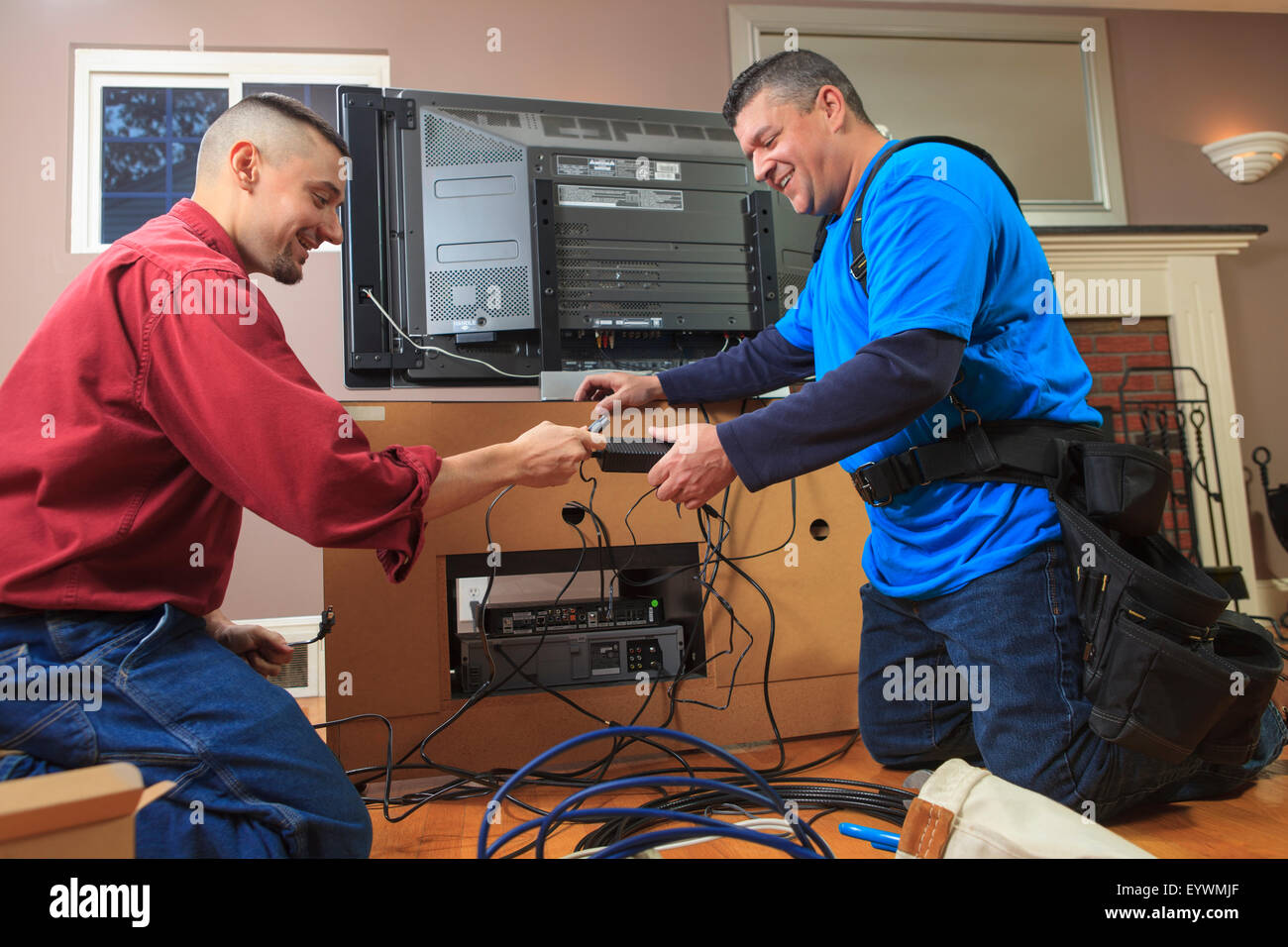 Cable installer working with home owner behind TV Stock Photo Alamy