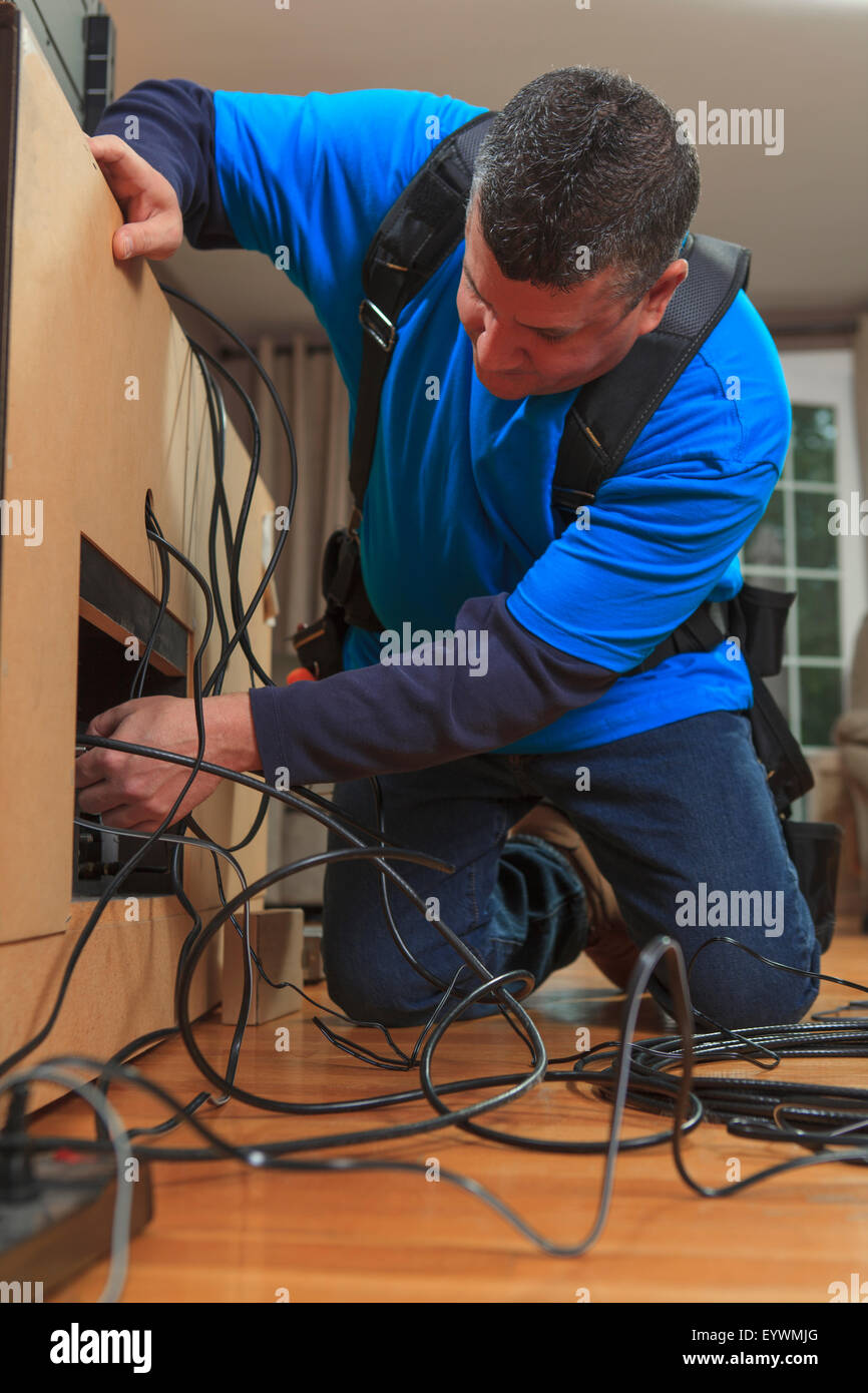 Cable installer working in a home behind the TV Stock Photo Alamy