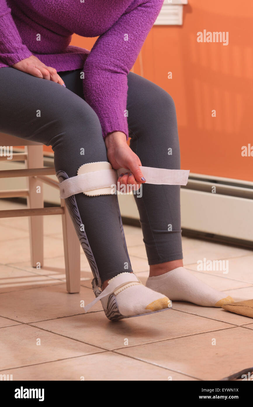 Young woman with right sided Cerebral Palsy putting a brace on her foot ...