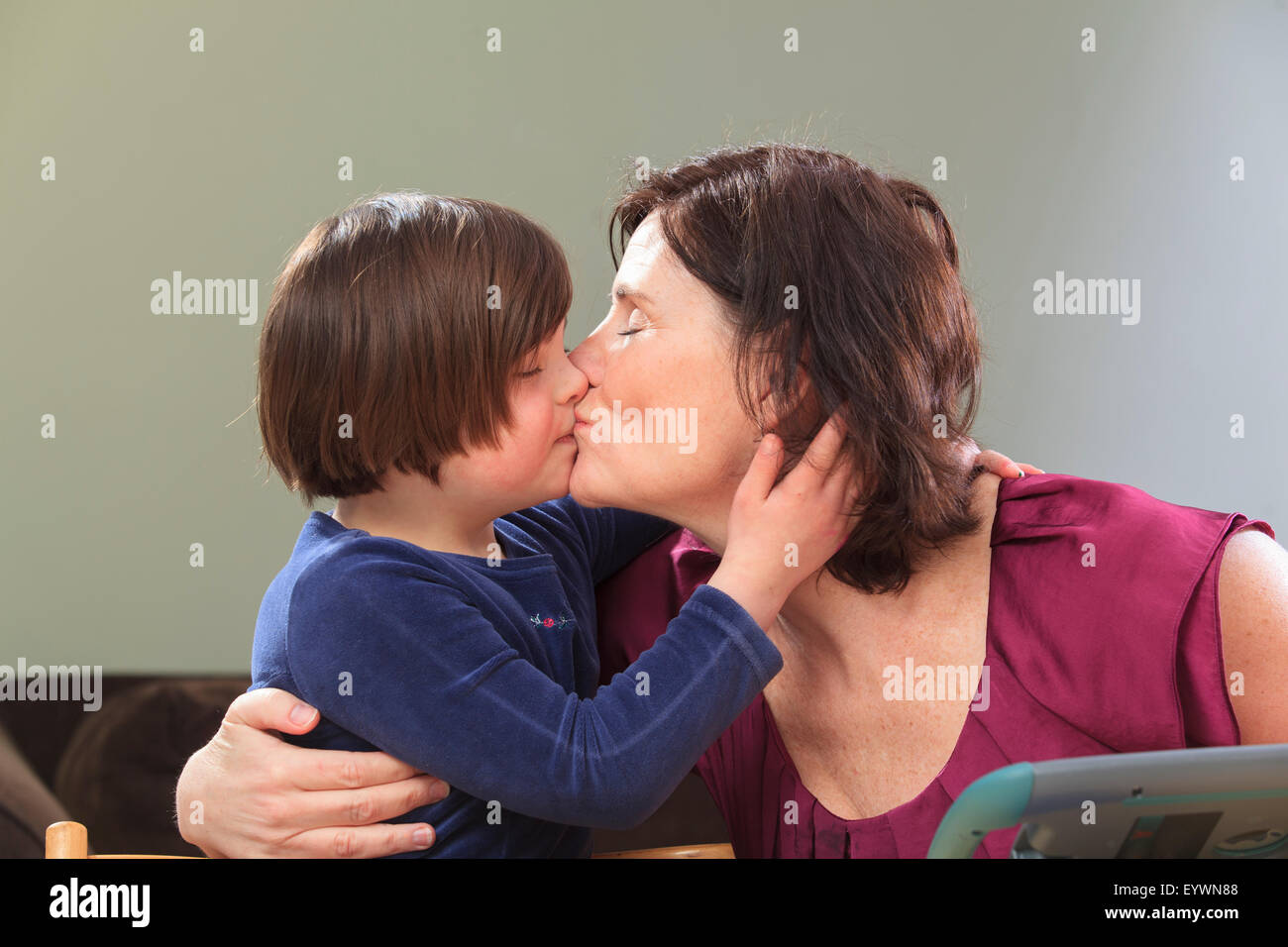 Little girl with Down Syndrome kissing her Mom Stock Photo