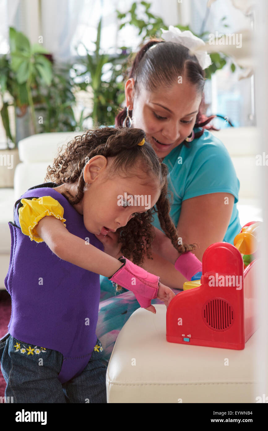 Mother helping small daughter with Cerebral Palsy play with a toy Stock