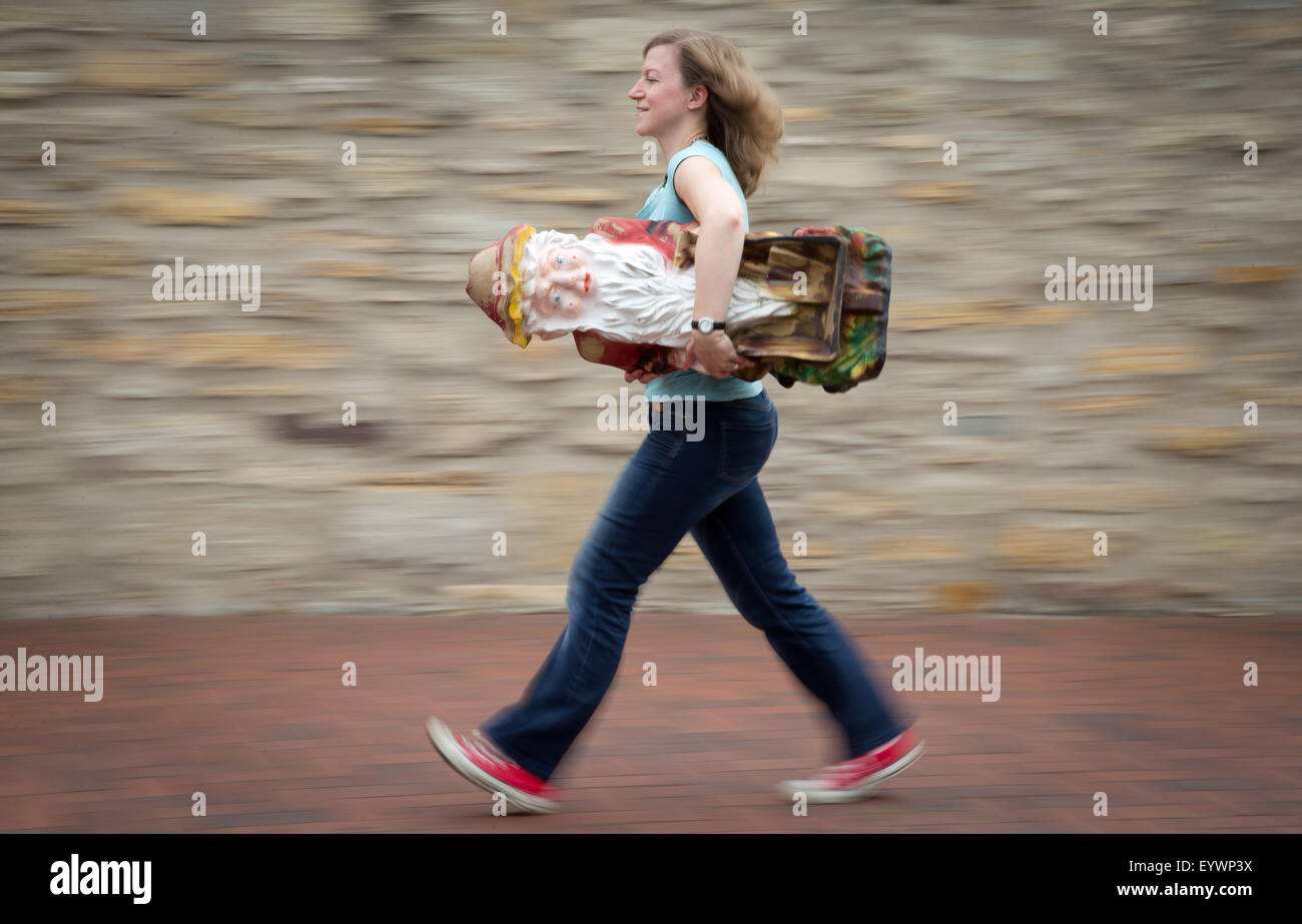 ILLUSTRATION - Project supervisor Lisa Mach carries a garden gnome in Osnabrueck, Germany, 04 August 2015. The cultural project office has launched a competition which will award prizes to the seven most popular garden gnomes of the city. Photo: Friso Gentsch/dpa Stock Photo