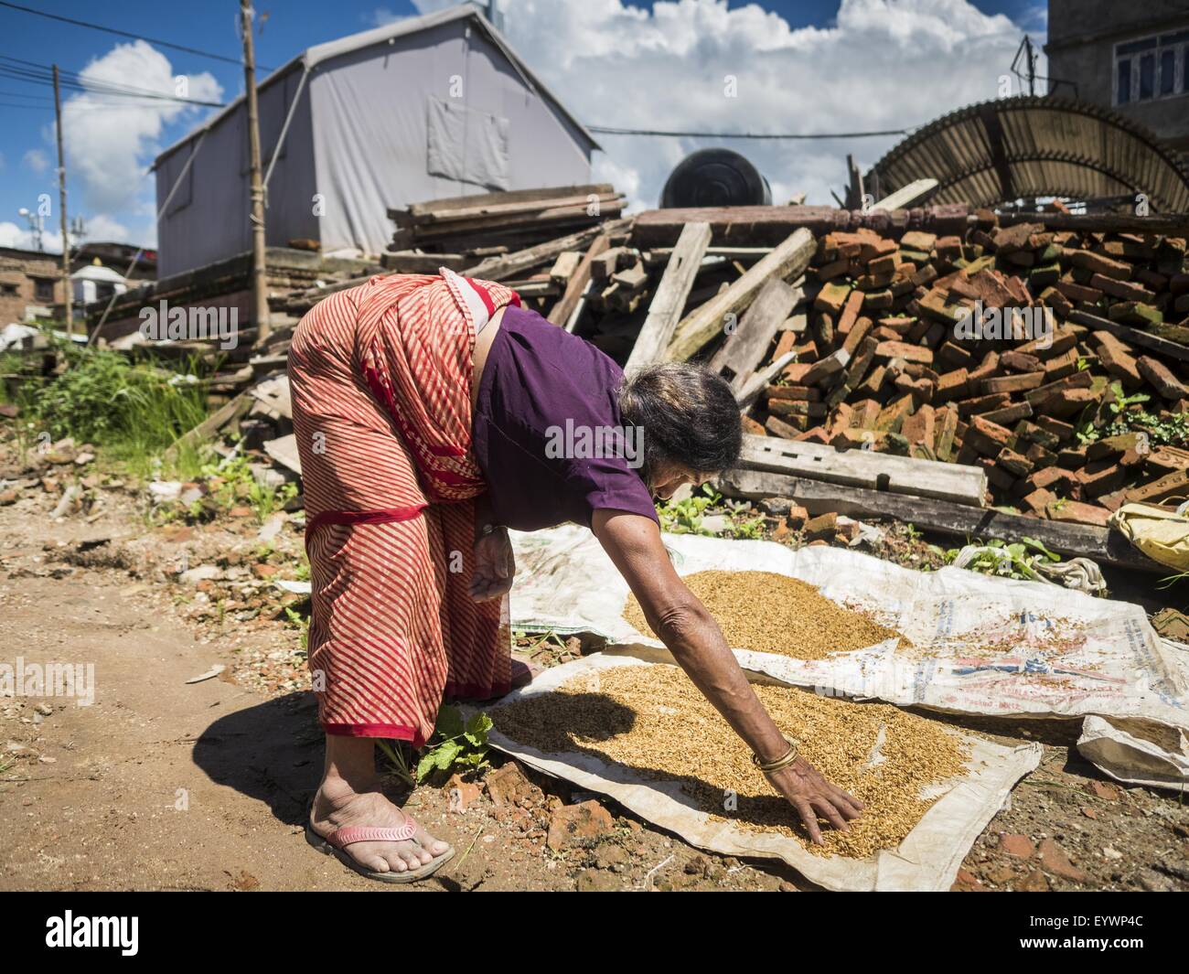 Sankhu, Central Region, Nepal. 3rd Aug, 2015. A woman whose home was destroyed by the earthquake dries rice in front of the rubble of her home in Sankhu, a community about 90 minutes from central Kathmandu. The Nepal Earthquake on April 25, 2015, (also known as the Gorkha earthquake) killed more than 9,000 people and injured more than 23,000. It had a magnitude of 7.8.  It was the worst natural disaster to strike Nepal since the 1934 Nepal''“Bihar earthquake. © ZUMA Press, Inc./Alamy Live News Stock Photo
