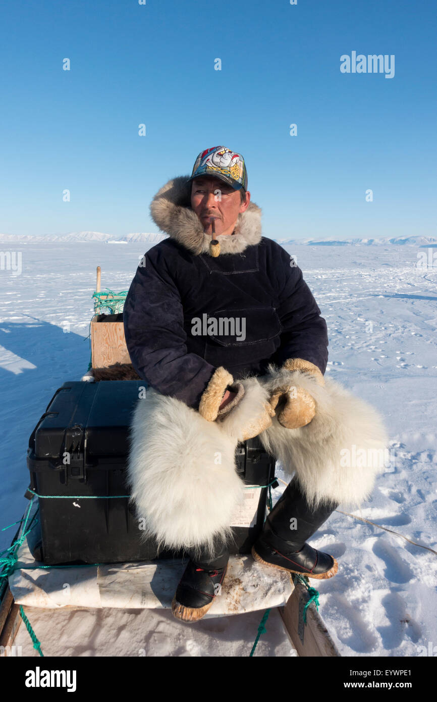 Inuit hunter smoking a pipe on the sea ice near Herbert Island, Greenland, Denmark, Polar Regions Stock Photo