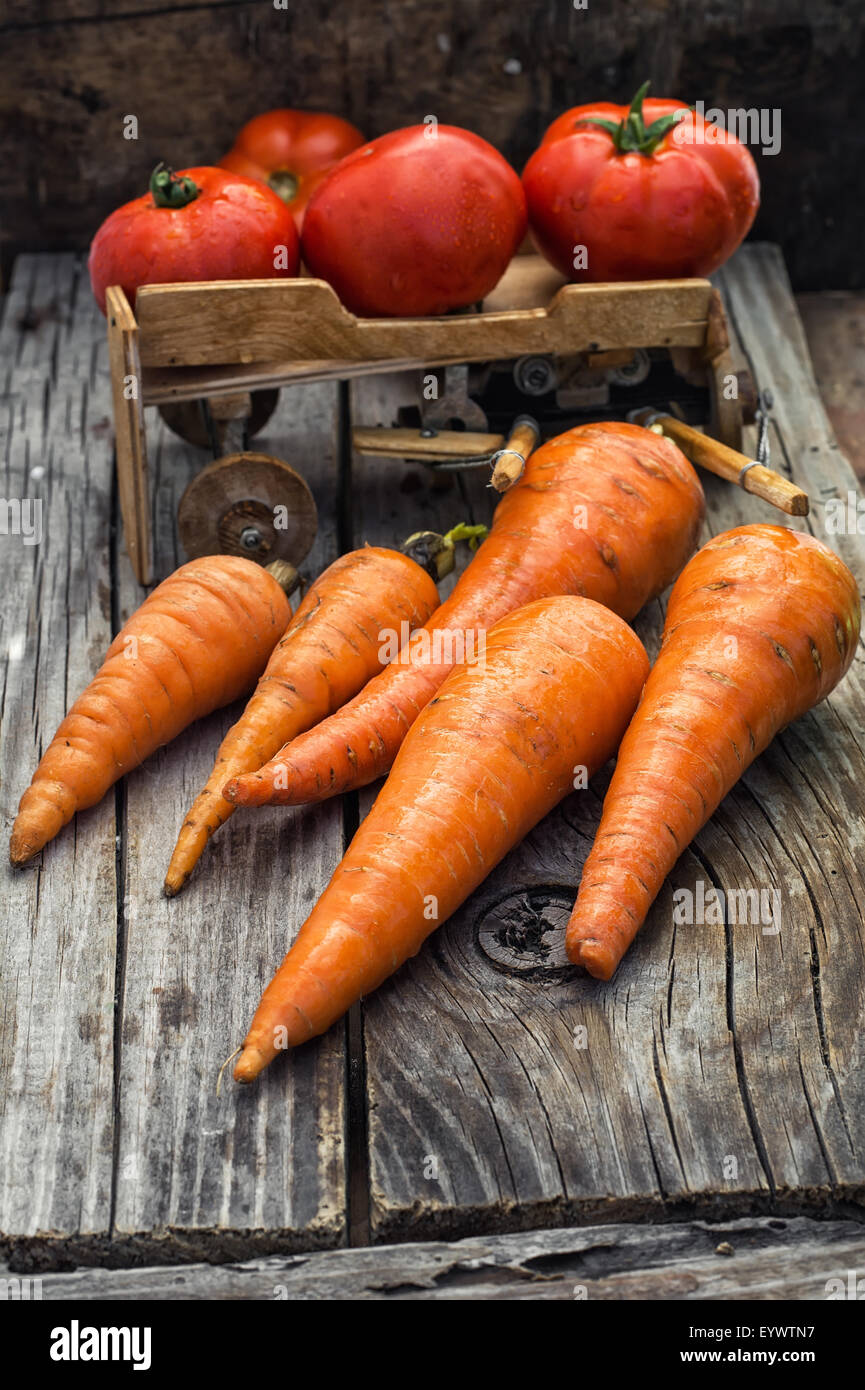 fresh carrots and fruits of tomato in the background is symbolic of  farmer's wagon Stock Photo