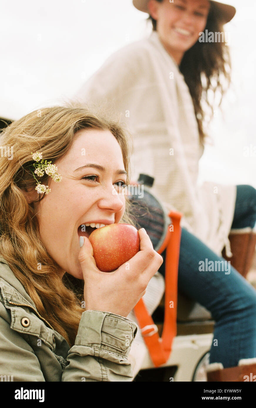 Two young women, one biting into an apple. Stock Photo