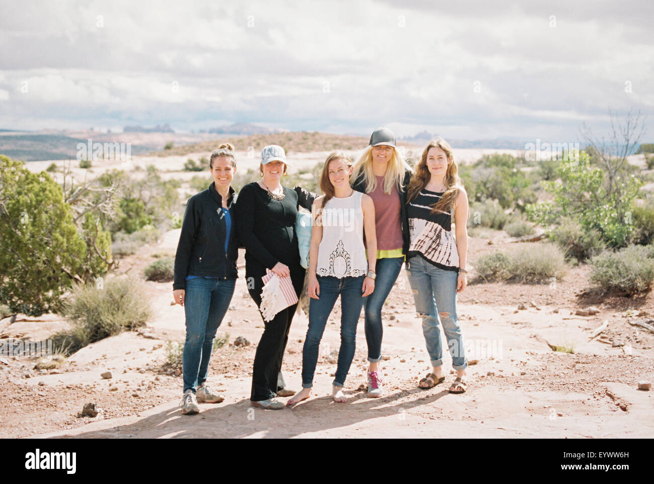 Group of five women, friends standing side by side in a desert landscape smiling. Stock Photo