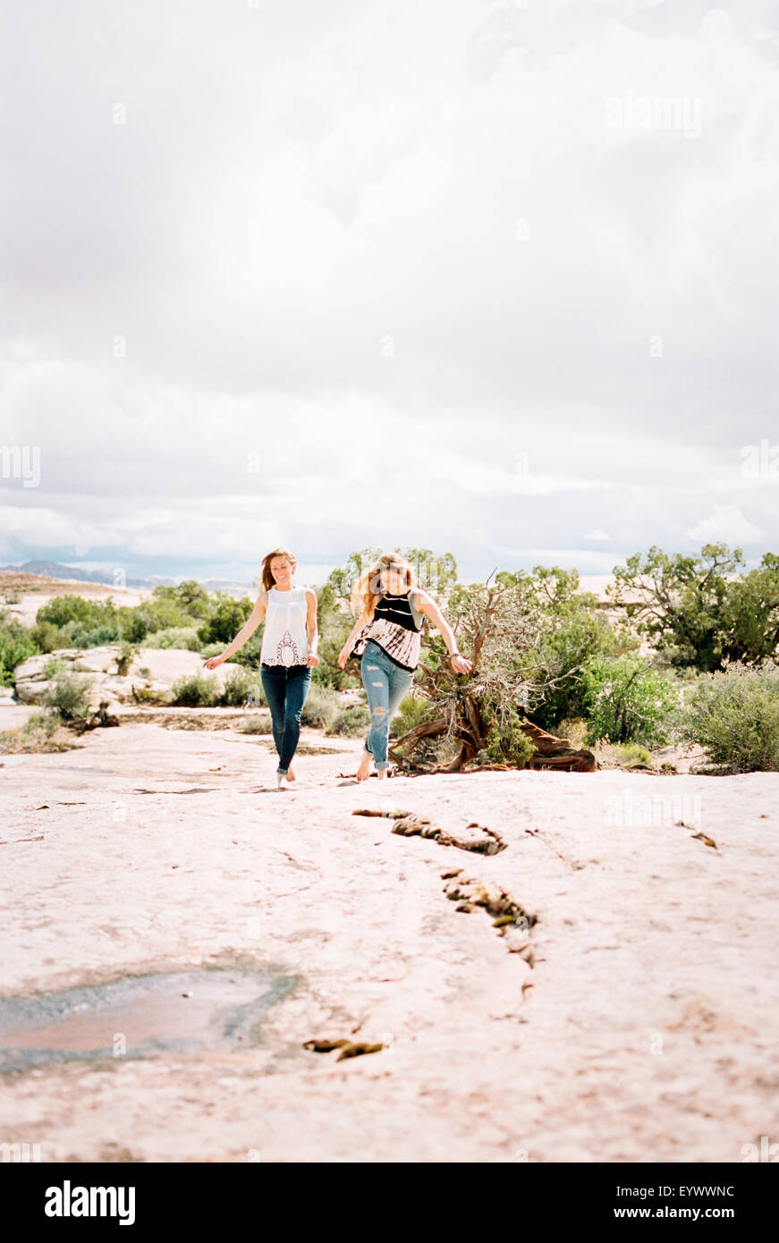 Two barefoot women walking in a desert. Stock Photo