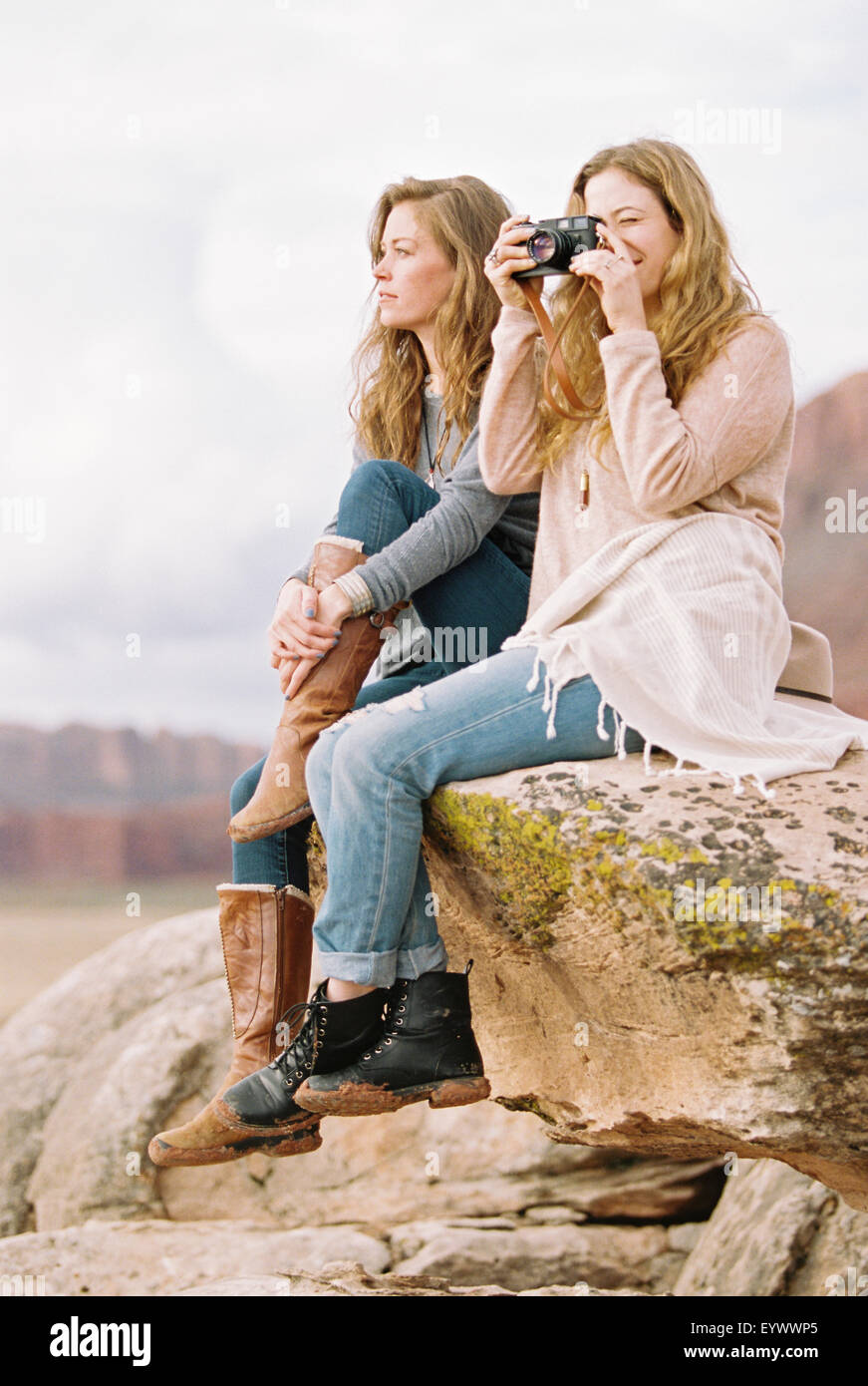 Two women sitting on rock one taking picture Stock Photo