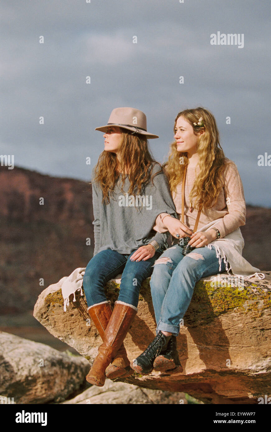 Two women wearing leather boots on rock in desert Stock Photo