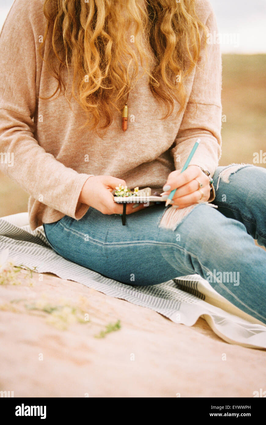 Woman sitting in a desert notebook and pencil. Stock Photo