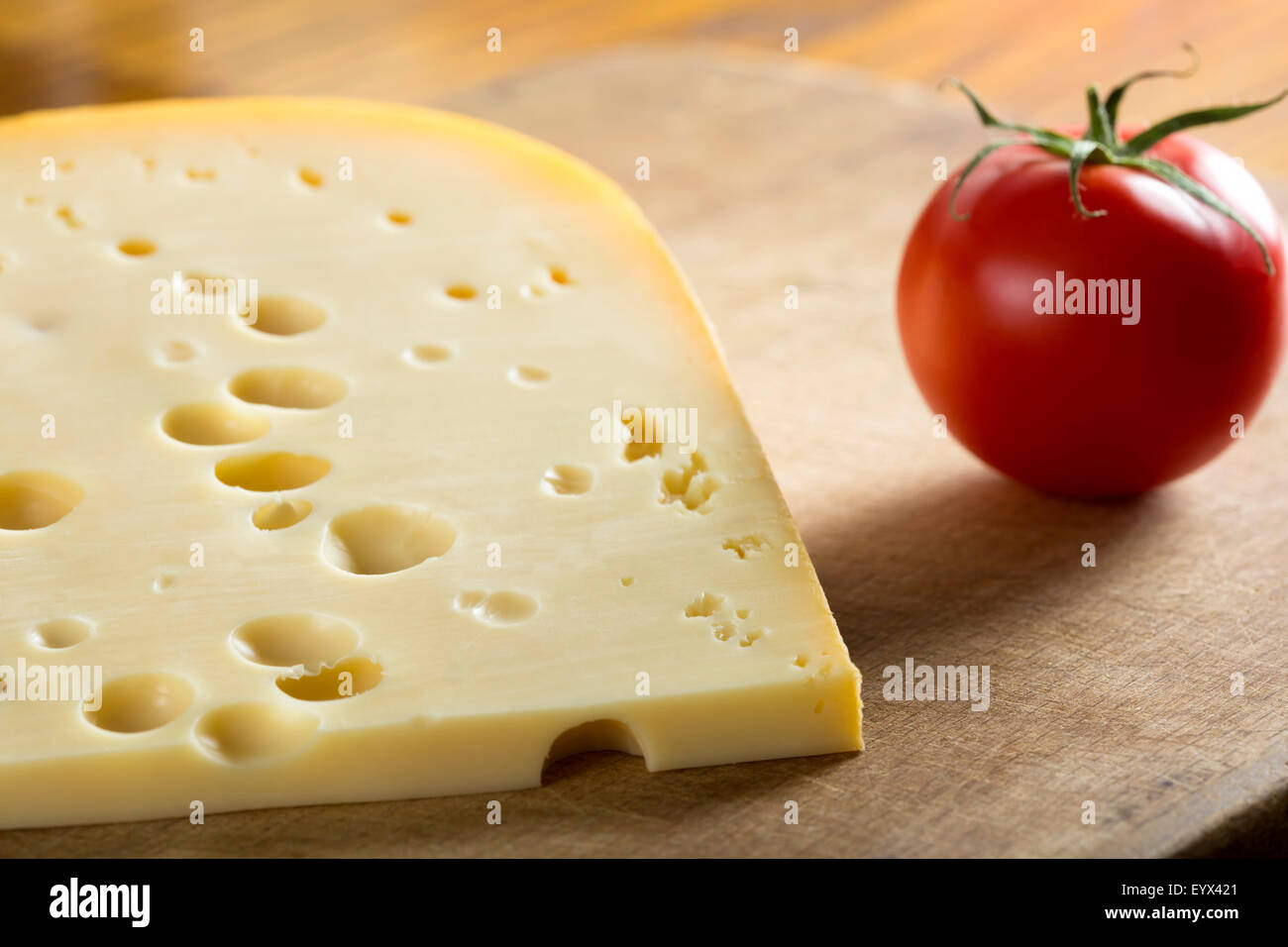 Swiss Emmental Cheese and tomato over wood background Stock Photo