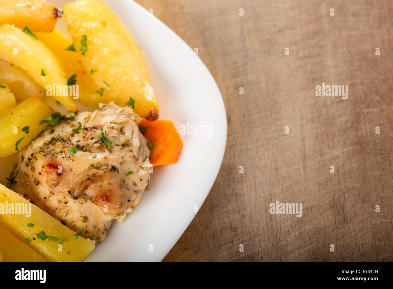 Barbecued chicken leg with baked potatoes with parsley on plate Stock Photo