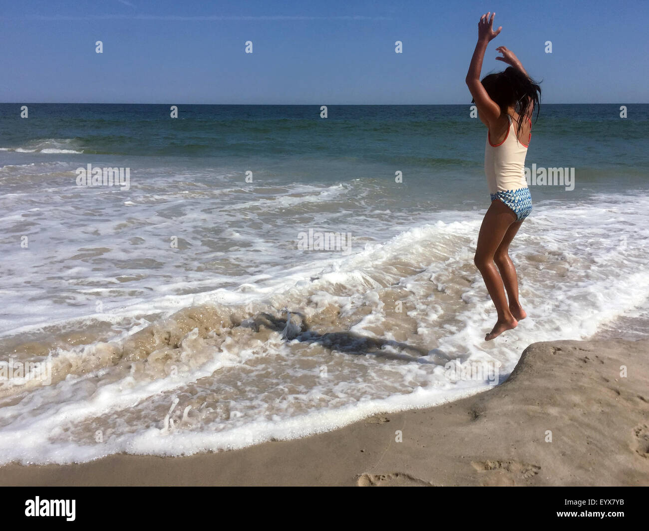 A 5year old girl in a bathing suit jumps into the surf on Ocean Beach