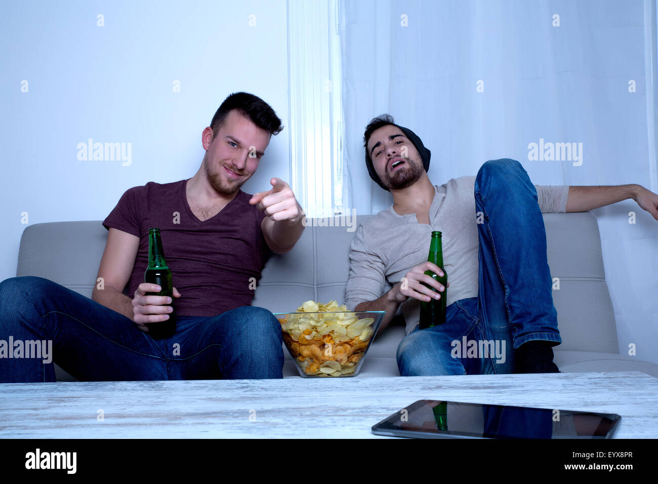 Two guys watching tv, drinking beer, eating crisps at home Stock Photo ...