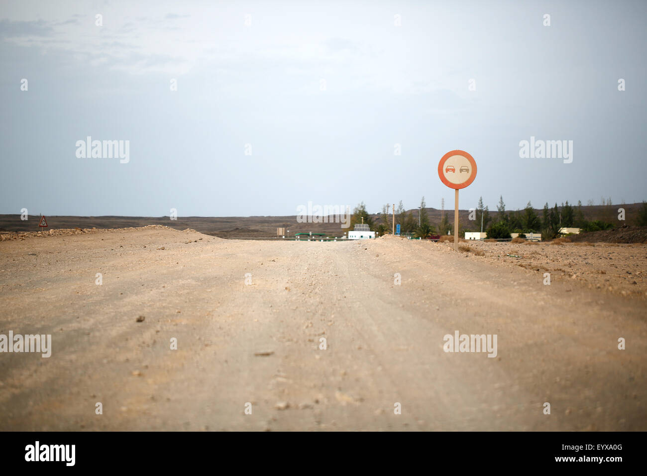 A dirt track road in Lanzarote, Spain. The road has a dried mud surface but is well used with a no overtaking sign. Stock Photo