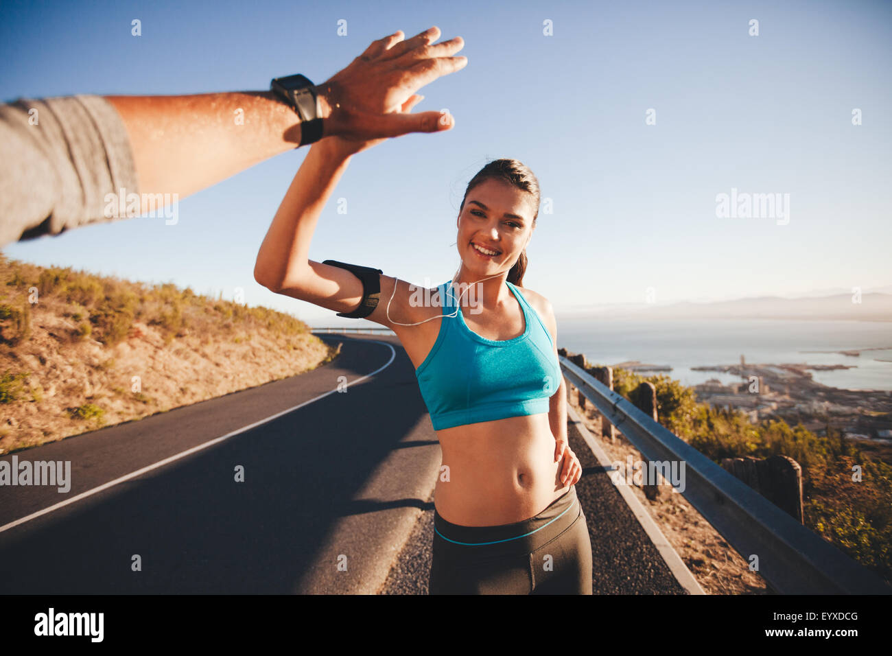 Fit young woman giving high five to her boyfriend after a run. POV shot of couple high fiving on country road in morning. Stock Photo