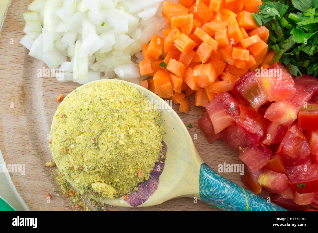 Wooden spoon with spices and colorful sliced vegetables on the board ready for cooking Stock Photo