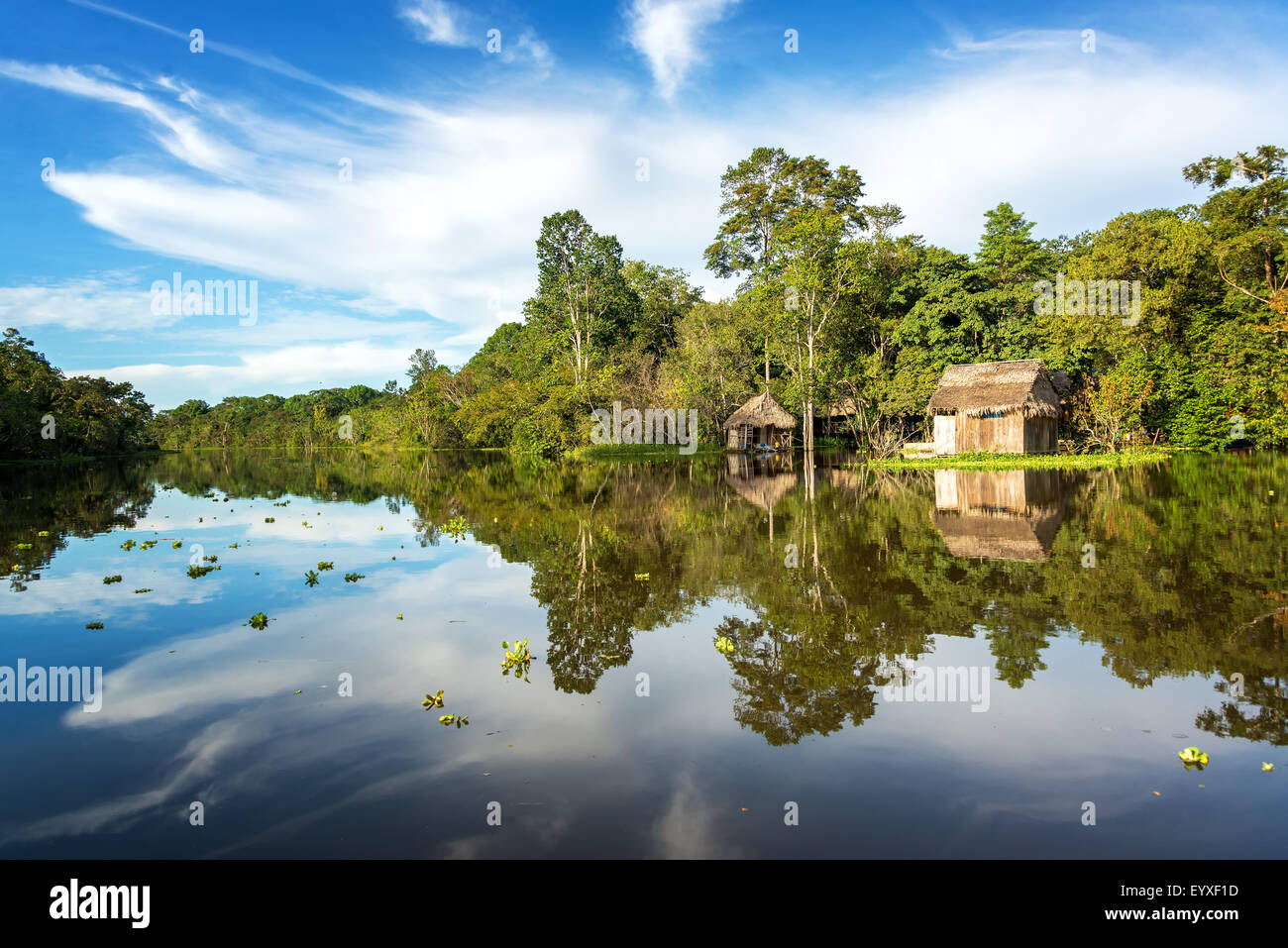 Small wooden shack in the Amazon rain forest with a beautiful reflection on the Yanayacu River near Iquitos, Peru Stock Photo