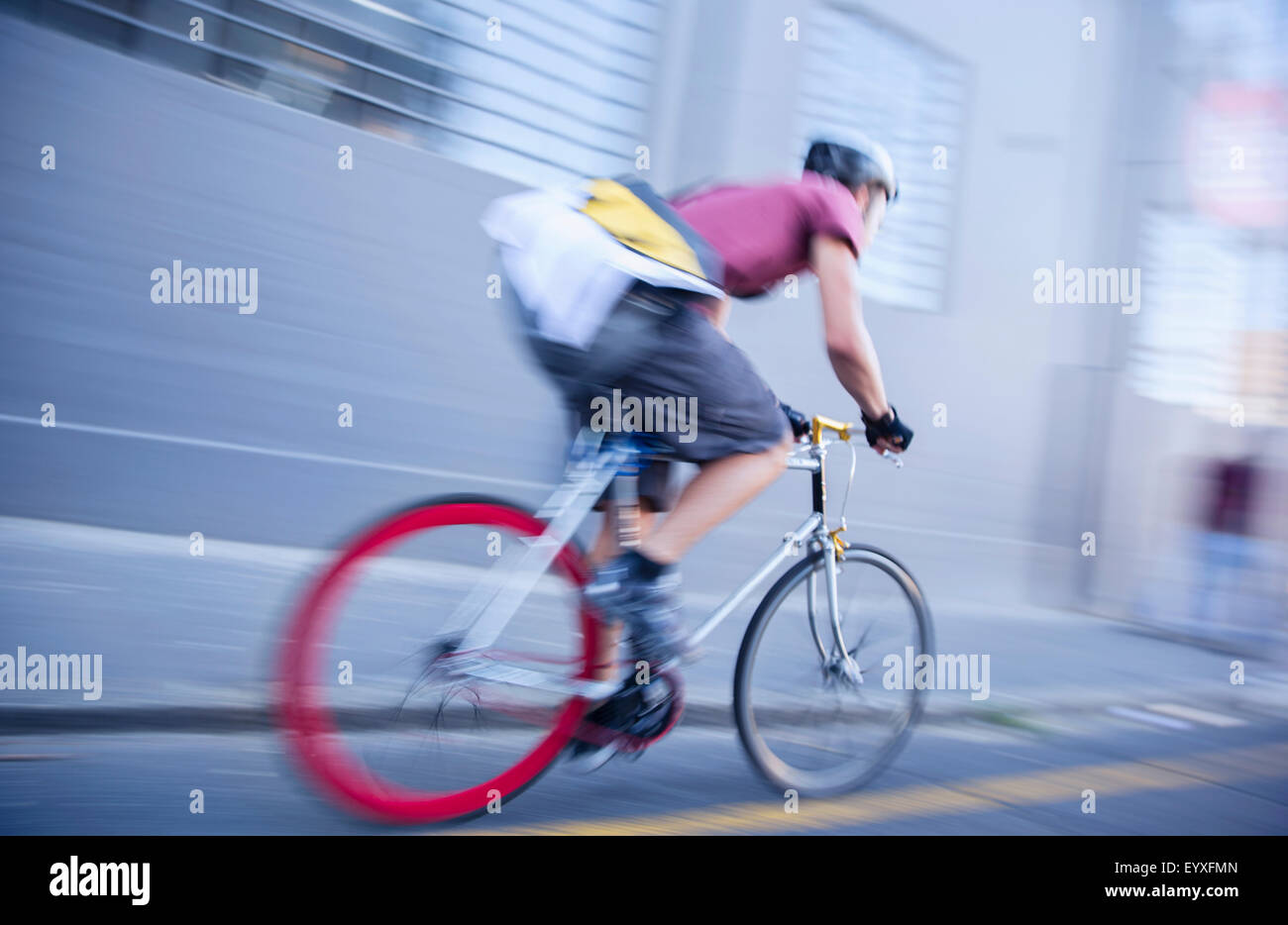 Bicycle messenger speeding down urban street Stock Photo