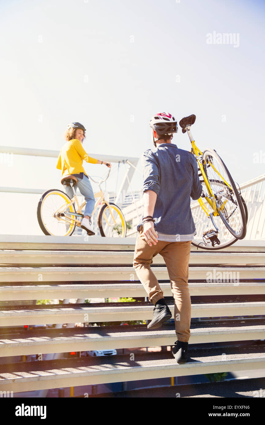 Man in helmet carrying bicycle up urban stairs Stock Photo