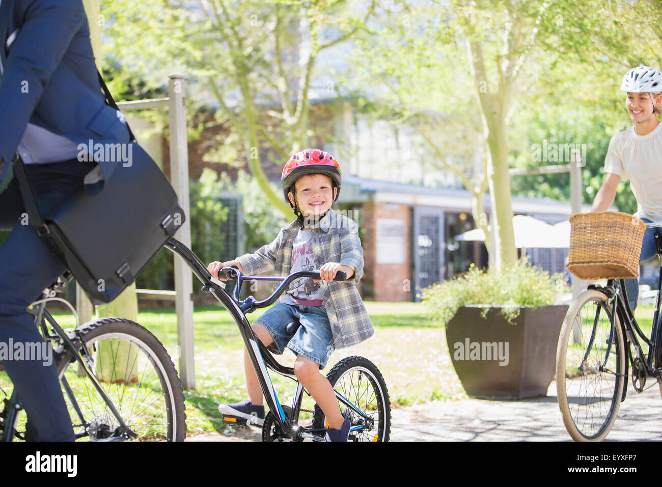 Portrait smiling boy in helmet riding tandem bicycle with father in park Stock Photo