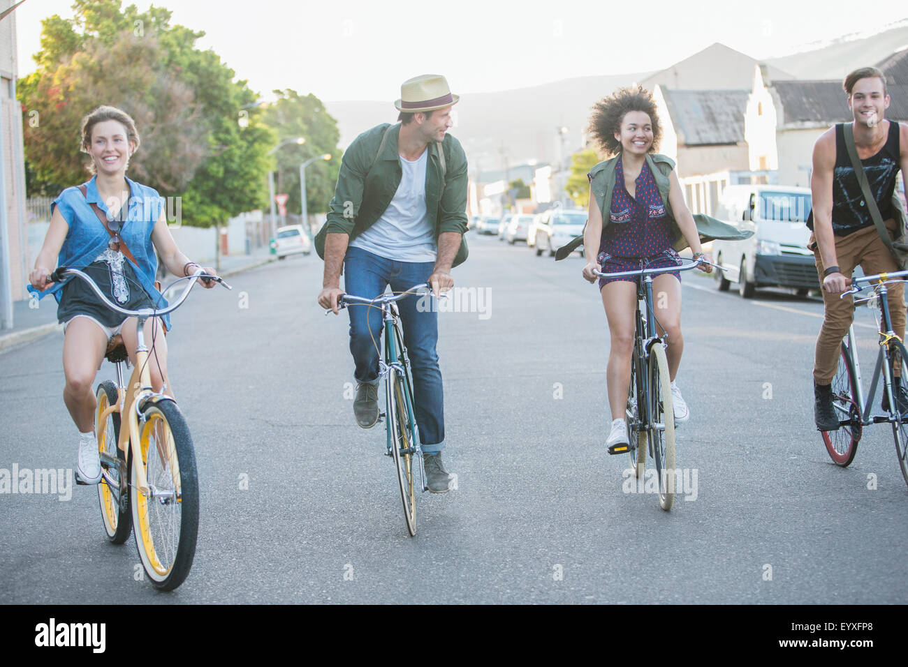 Friends riding bicycles in a row on street Stock Photo