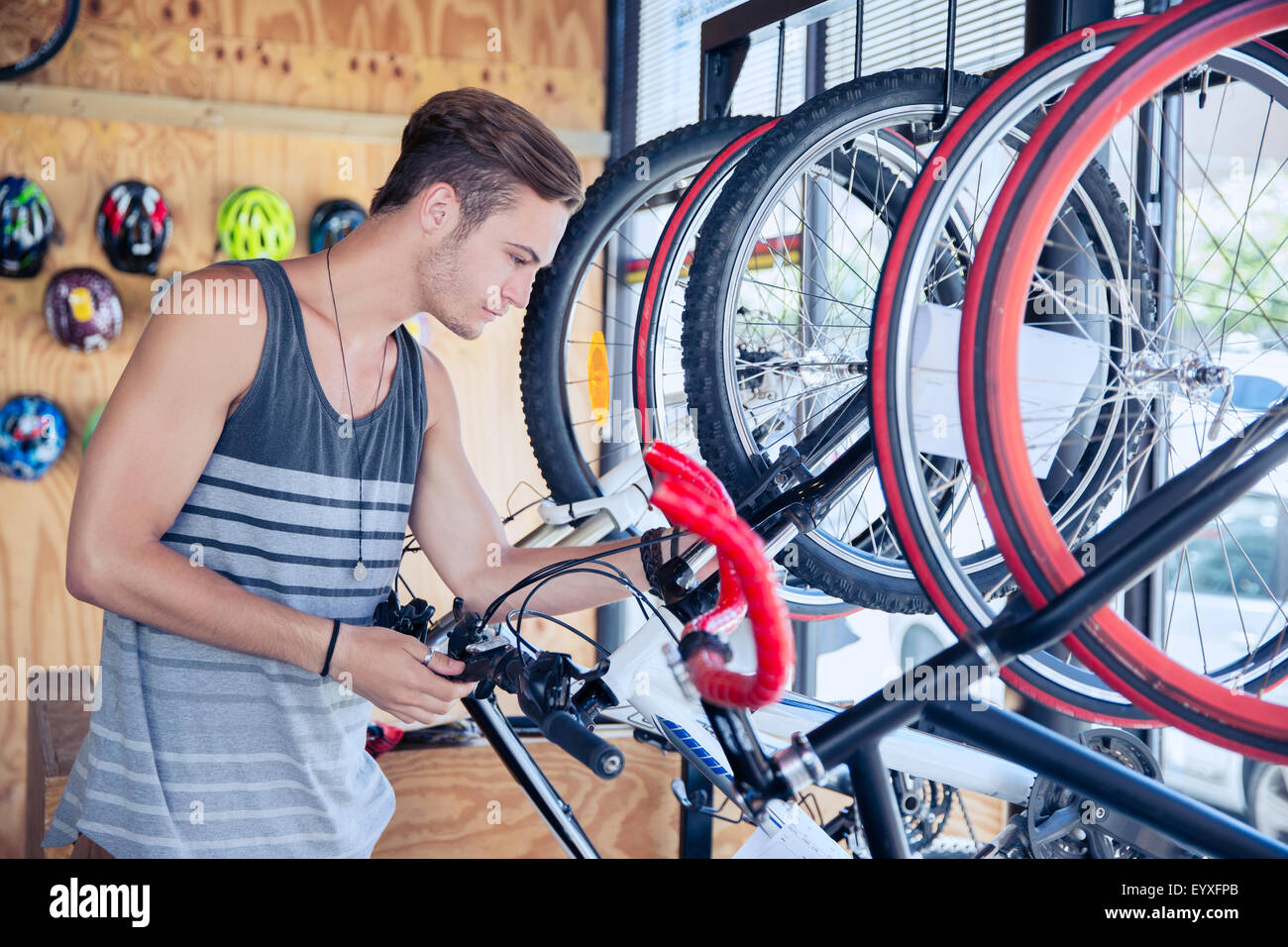 Young man examining bicycle on rack in bicycle shop Stock Photo