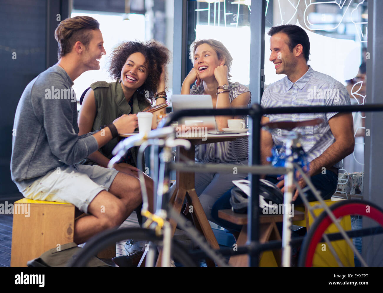 Friends hanging out in cafe behind bicycle Stock Photo