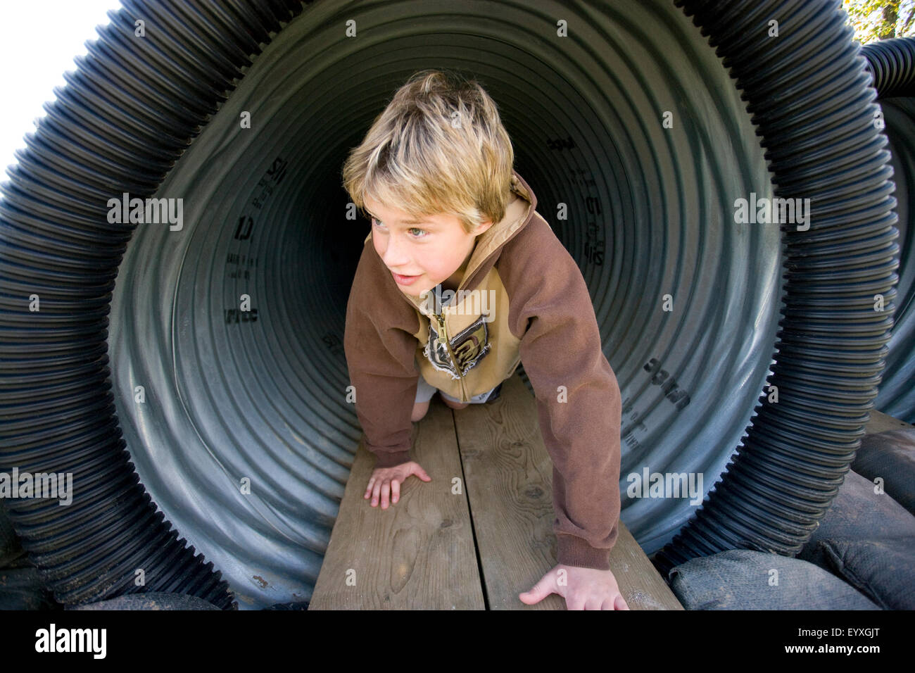 boy crawling through tunnel in playground Stock Photo