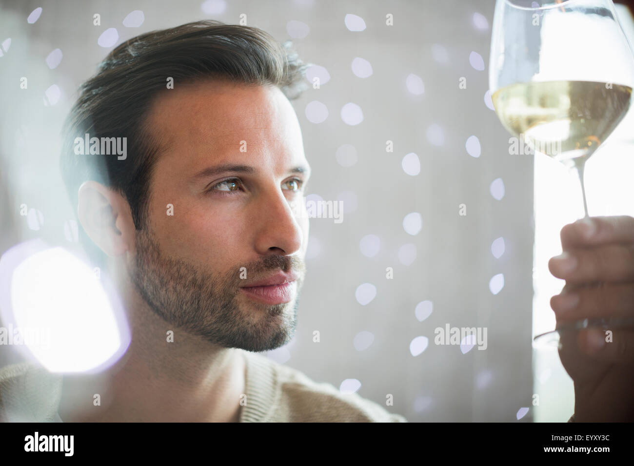 Close up serious man examining white wine Stock Photo