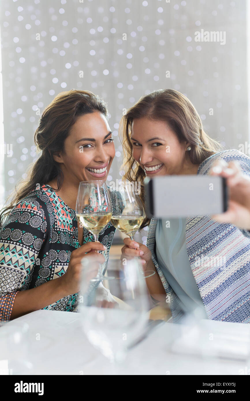 Women with white wine taking selfie with camera phone in restaurant Stock Photo