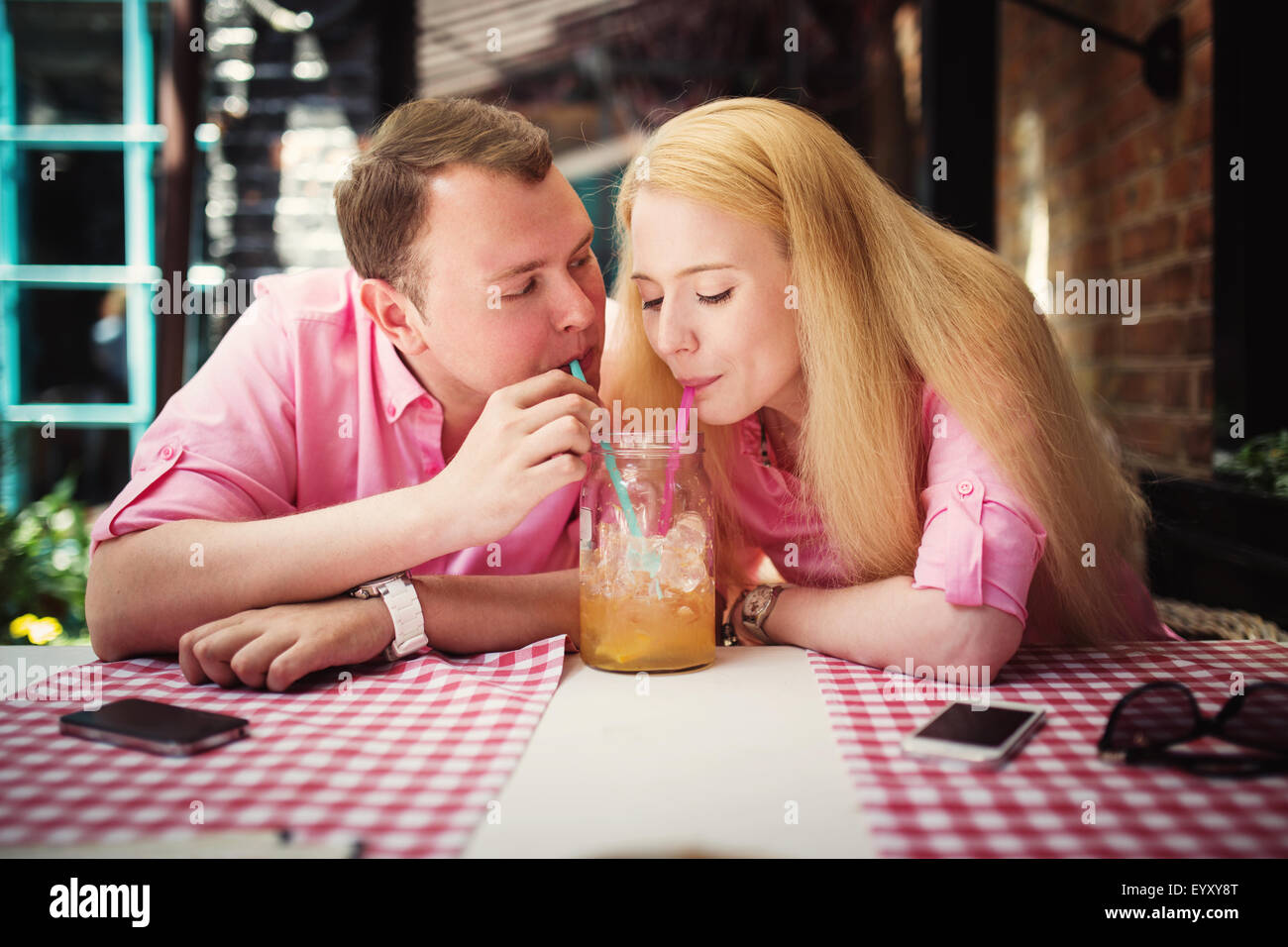 Cheerful couple surfing the web, looking a photo on smartphone, summer outdoor cafe Stock Photo