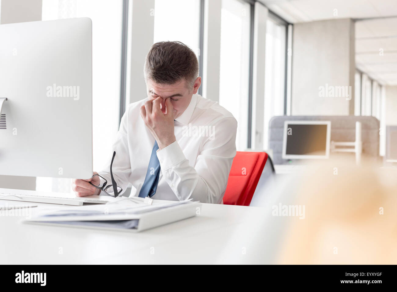 Tired businessman rubbing eyes at computer in office Stock Photo