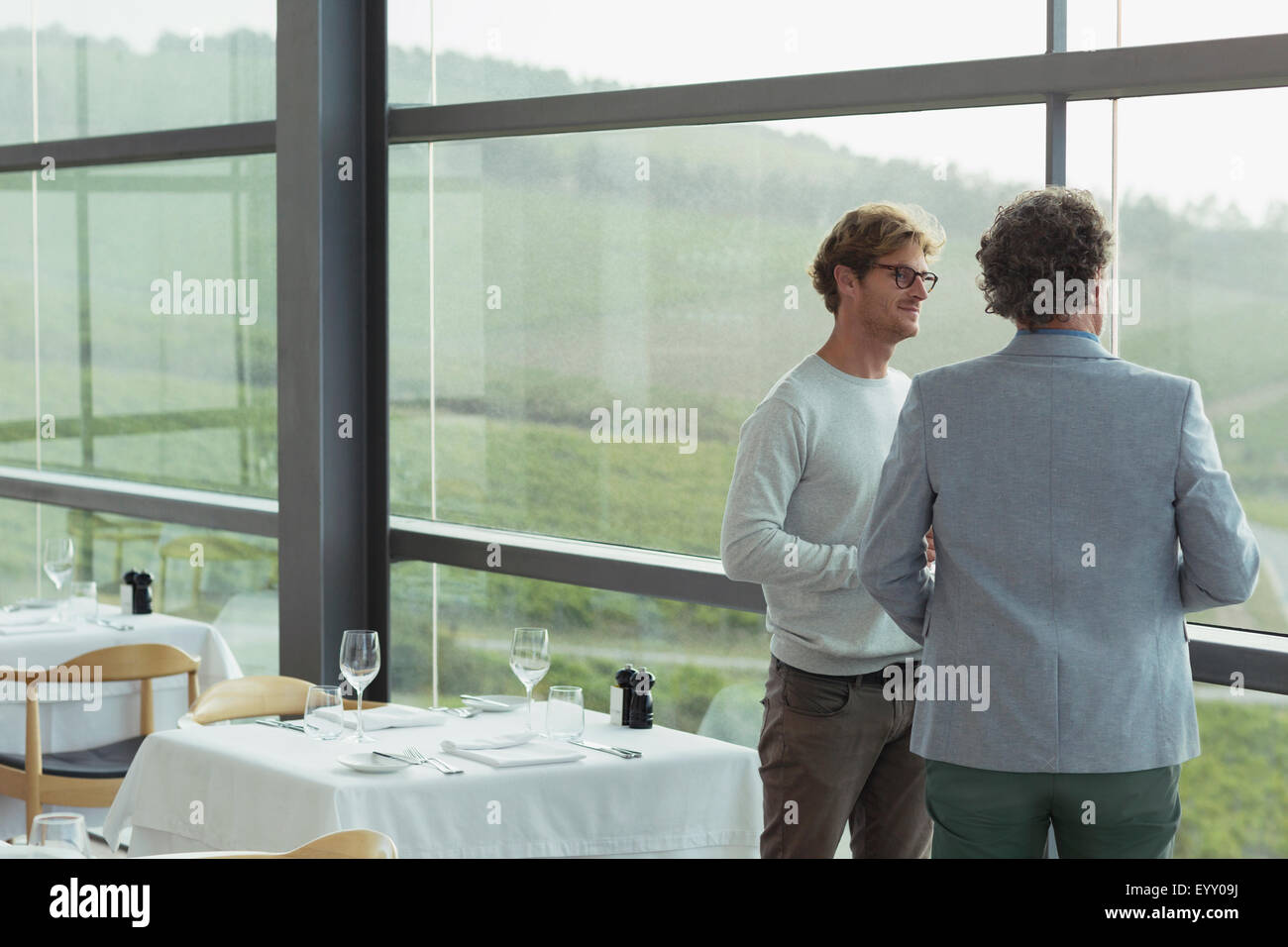 Men talking at winery dining room window Stock Photo
