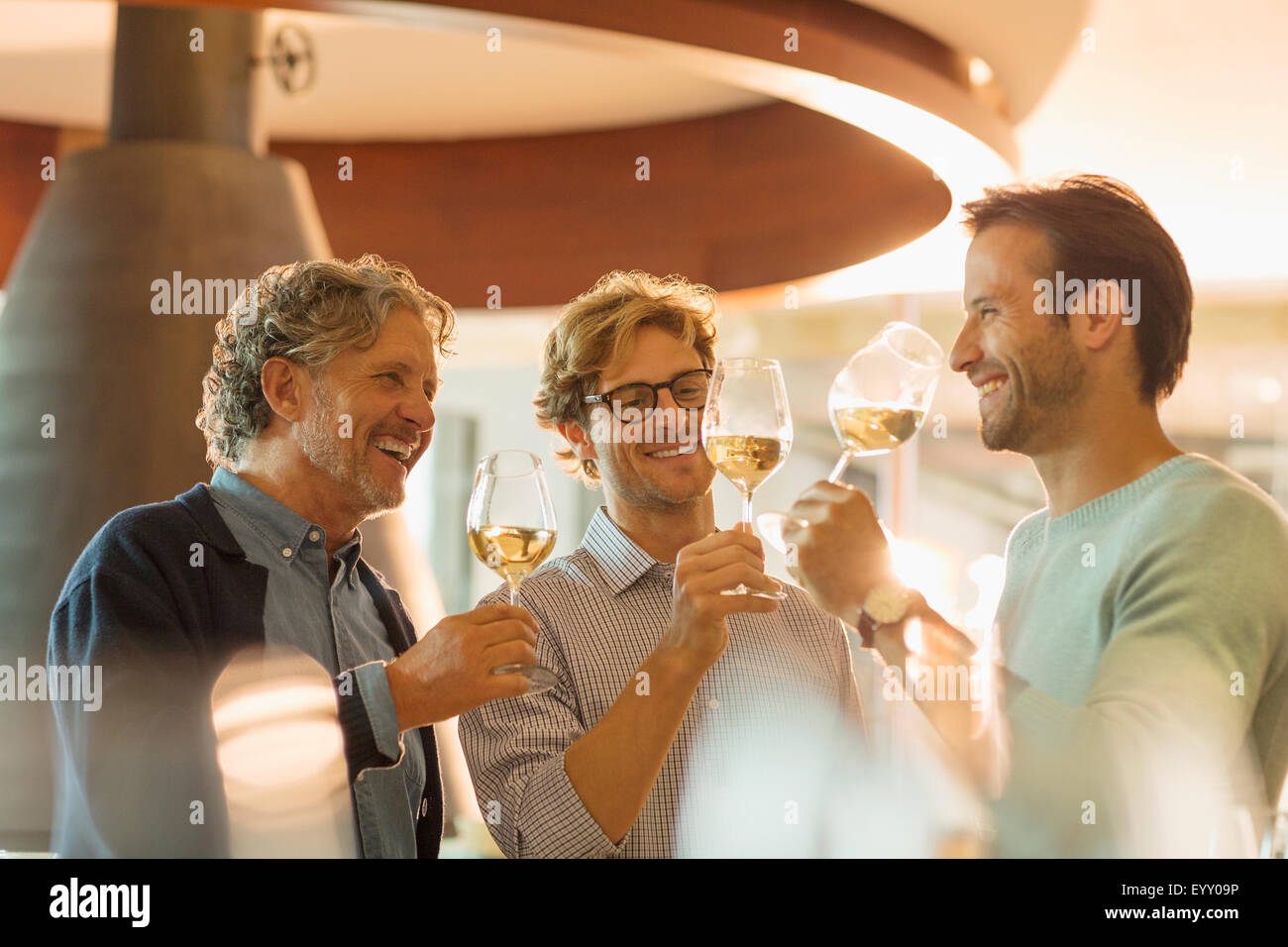 Men wine tasting white wine in winery tasting room Stock Photo