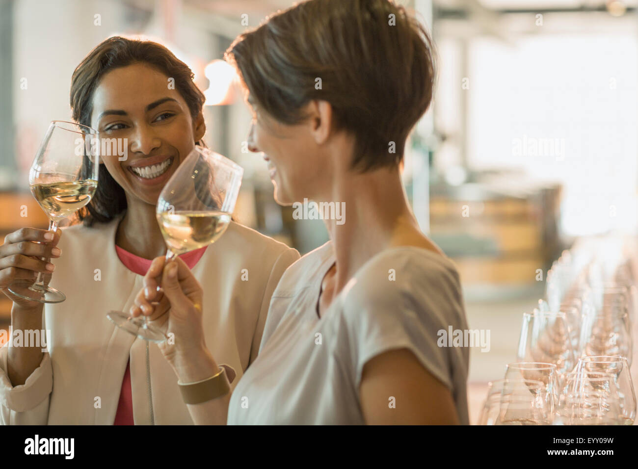 Smiling women wine tasting white wine in winery tasting room Stock Photo