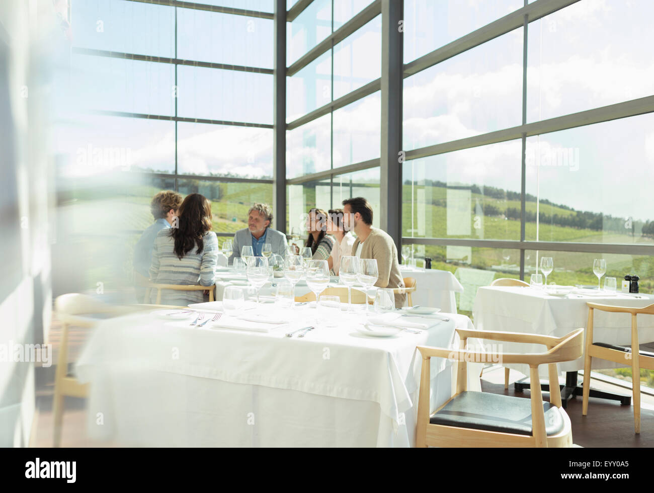 Friends sitting at table in sunny winery dining room Stock Photo
