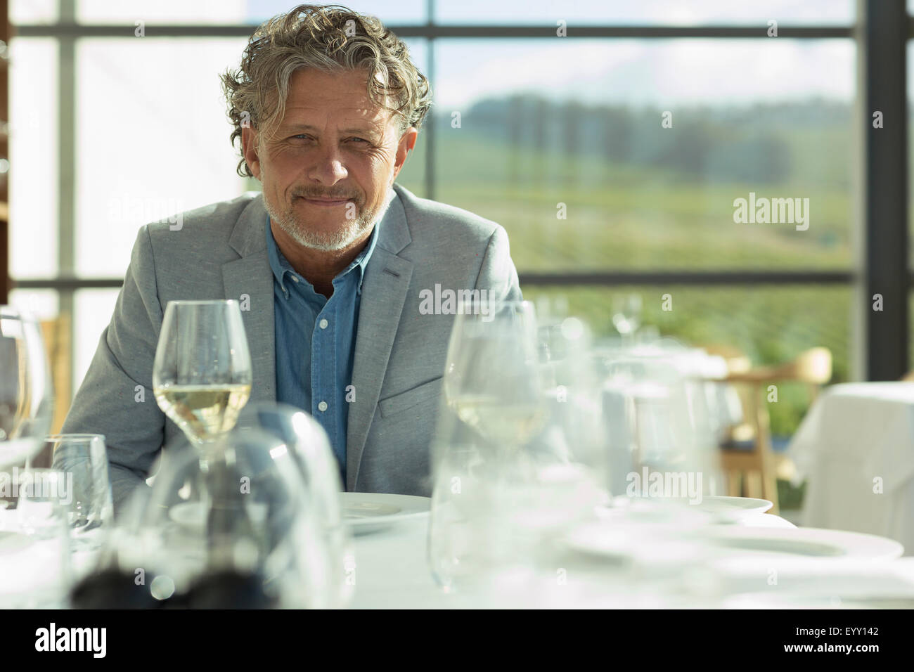 Portrait confident man with white wine at sunny restaurant table Stock Photo