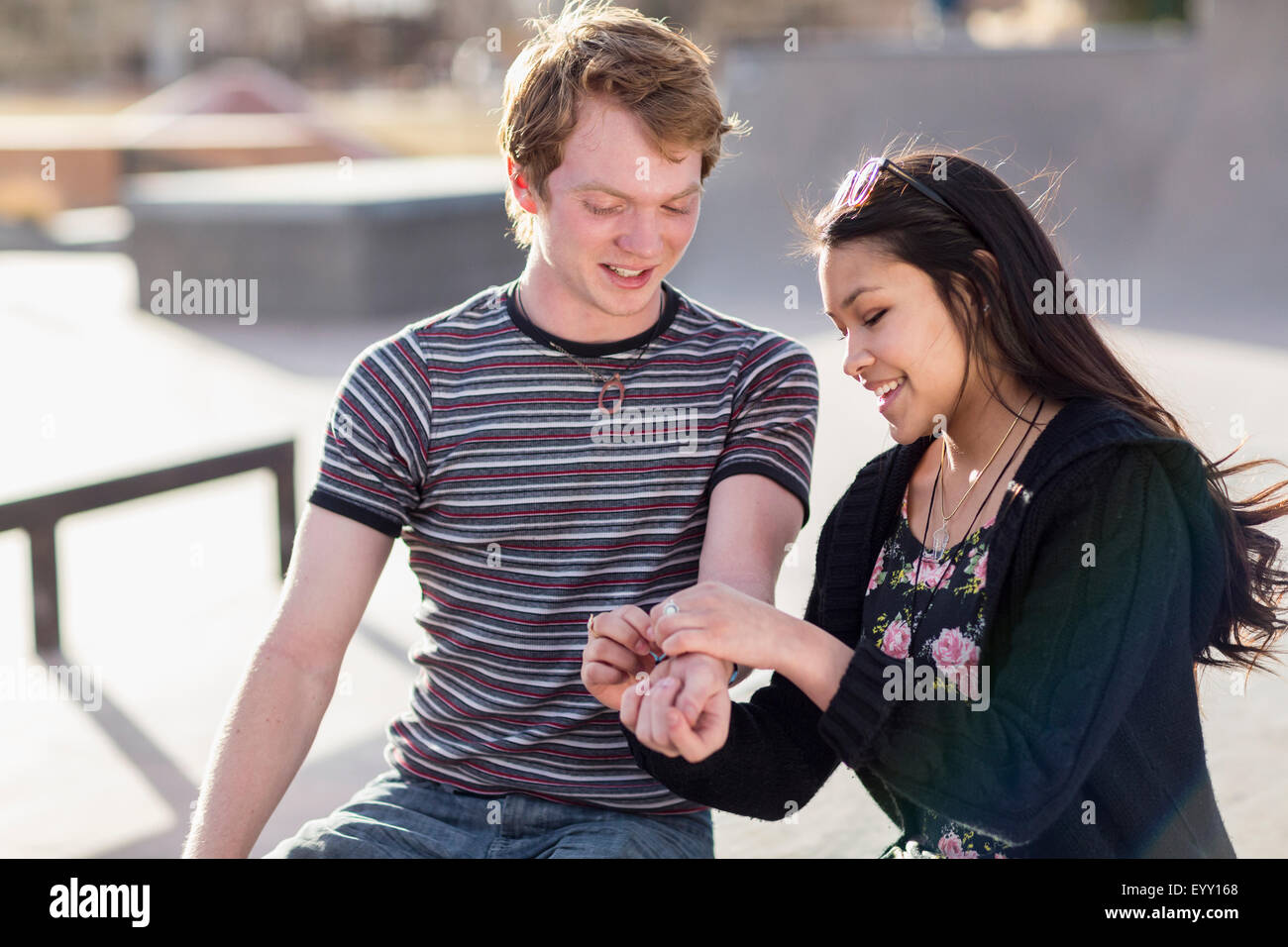 Teenage girl tying bracelet around wrist of boyfriend Stock Photo
